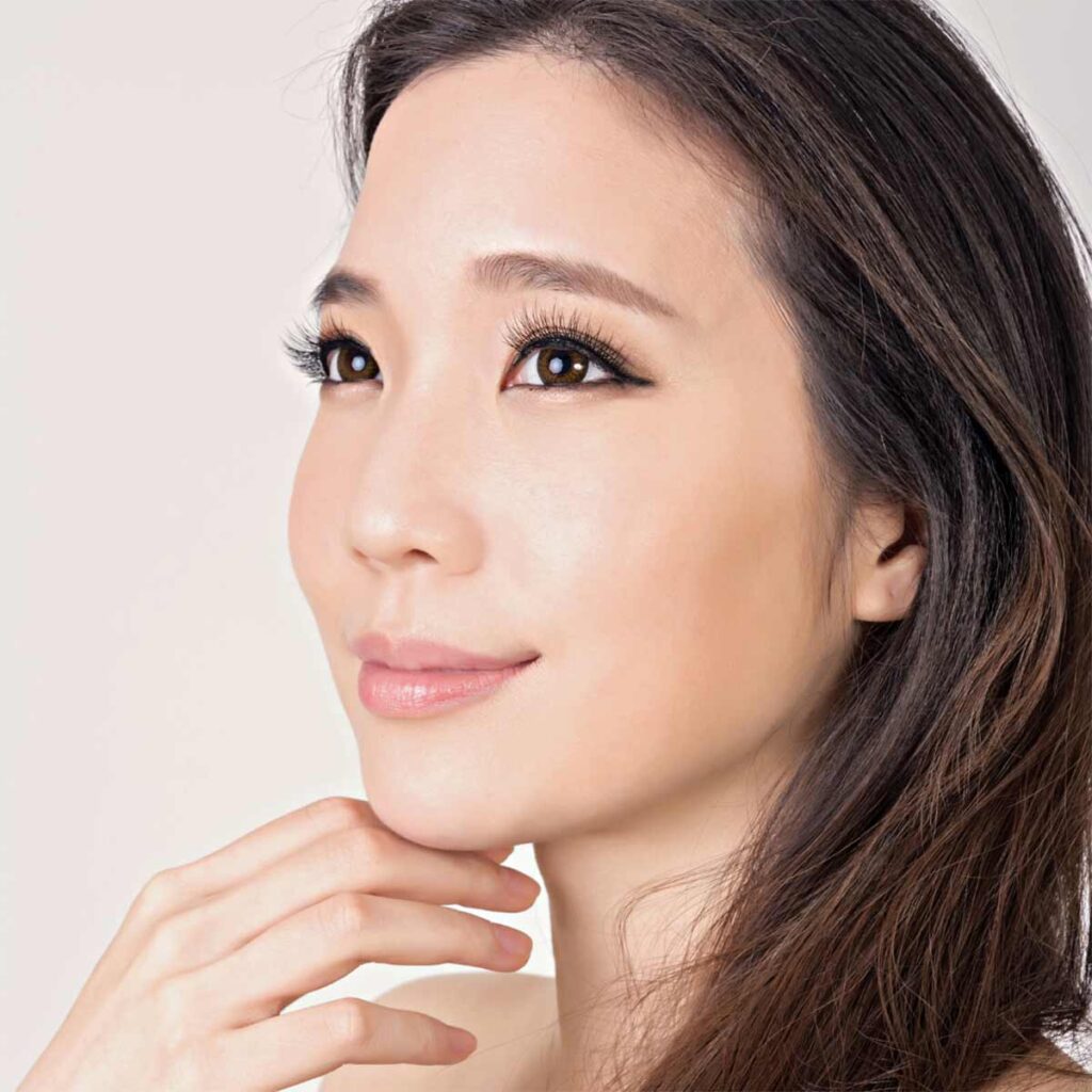 face of women with almond shaped eyes and brown hair side view with a slight smile